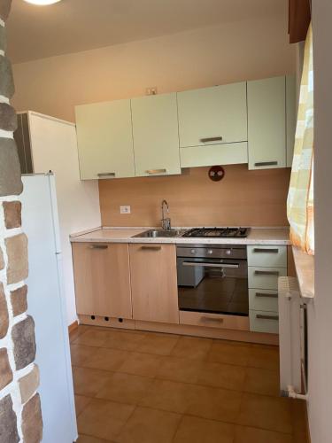 a kitchen with white cabinets and a sink and a stove at LE GEMME in Andalo