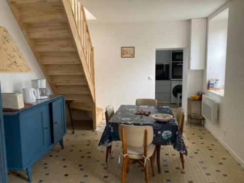 a dining room with a table and a blue cabinet at La maison du Cèdre in Châteauneuf-Val-de-Bargis
