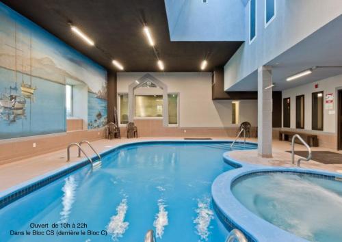 a swimming pool in a hotel room with a large swimming pool at Magog Waterfront Studio 106 in Magog-Orford