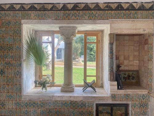 a room with a window with a column and a plant at Lella Kmar B&B avec piscine Sidi Bou Said in Sidi Bou Saïd