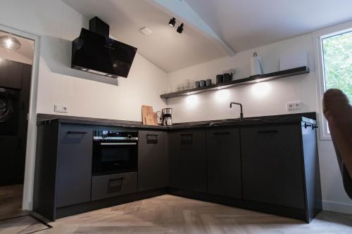 a kitchen with black cabinets and a sink at Fenna's Holiday Home in Exloo