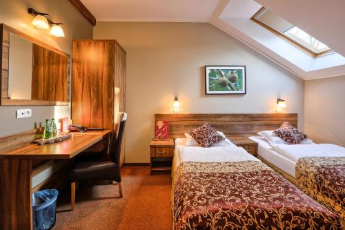 a hotel room with two beds and a desk at Hotel Dębowe Wzgórze Wellness & Spa in Jarnołtówek