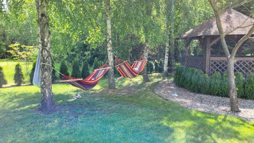two hammocks hanging from trees next to a gazebo at Hotel & Restauracja Wróblewscy in Karniewo