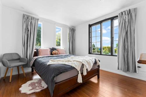 a bedroom with a bed and a chair and windows at Albert.T Home in Auckland