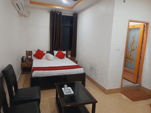 a bedroom with a bed and a chair and a table at Hotel Knight Inn Airport in Guwahati