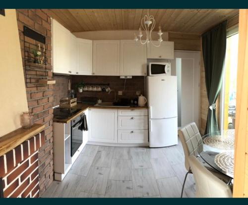 una cucina con mobili bianchi e un frigorifero bianco di Sielanka Mazurska Świętajno Aprt 2 a Świętajno