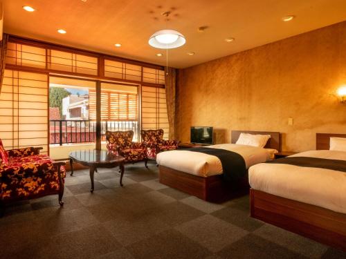 a hotel room with two beds and a table at Yukai Resort Unzen Toyokan in Obama