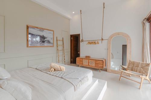 a white bedroom with a large bed and a chair at Sunset Villa in Munggu