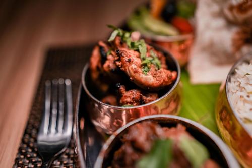 a table with two metal dishes of food and a fork at Distrikt 9 in Palakkad
