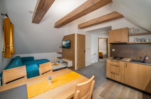 a kitchen and living room with a table and a blue couch at Rezort pri Jazere Podbanské in Vysoké Tatry