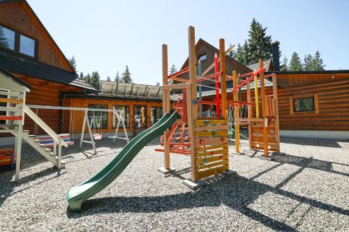 a playground with a slide in front of a cabin at Rezort pri Jazere Podbanské in Vysoké Tatry