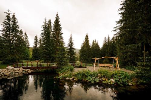 a wooden bridge over a river with a wooden archway at Rezort pri Jazere Podbanské in Vysoké Tatry