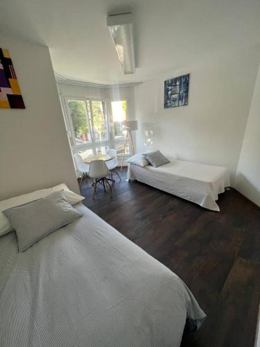 ein weißes Schlafzimmer mit 2 Betten und einem Tisch in der Unterkunft Basel-Stadt Gundeldingen Zimmer 401, WC in the hallway, outside the room in Basel