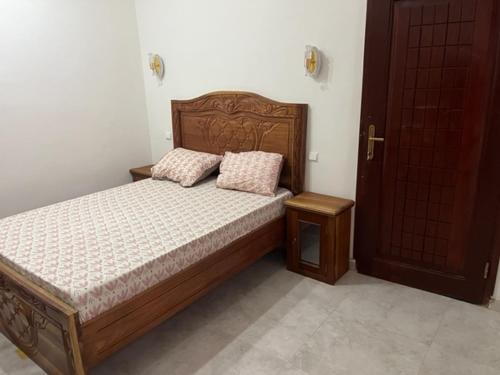 1 dormitorio con cama de madera y 2 almohadas en House of Flora, en Saint-Louis
