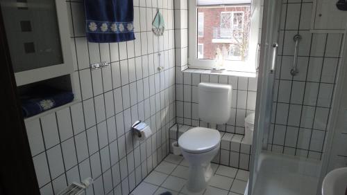 een wit betegelde badkamer met een toilet en een raam bij FEWO-bis-2-Pers-inmitten-den-Yachthafens-Ueckermuende-Stettiner-Haff-Ostsee in Ueckermünde