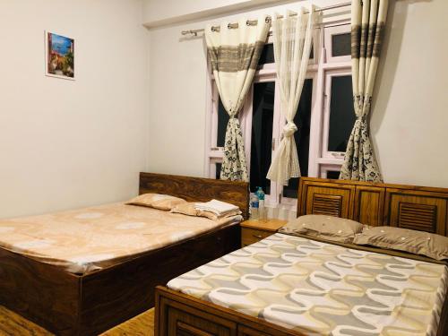 - 2 lits dans une chambre avec fenêtre dans l'établissement Sherpas Enclave, à Kalimpong