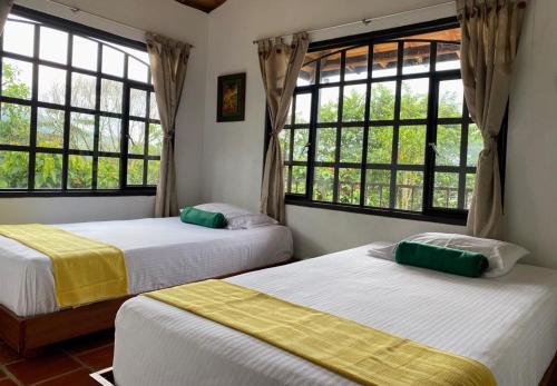 two beds in a room with two windows at Casas De Campo - El Paraíso in La Vega