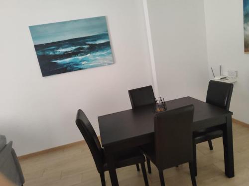 a black dining room table with chairs and a painting at S & K Apartment free indoor parking in Athens