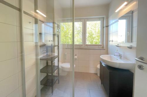 une salle de bain avec un lavabo et une douche en verre dans l'établissement Strandstrasse 21 Ferienwohnung Domizil Auszeit, à Kolpinsee