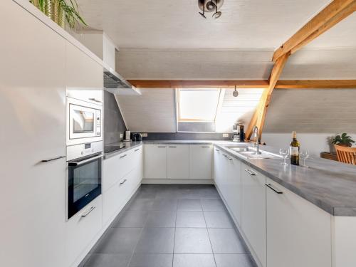 a white kitchen with white cabinets and a window at In de Wollekjes in Merksplas