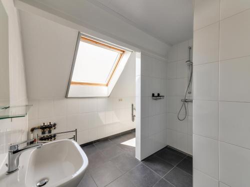 a white bathroom with a sink and a window at In de Wollekjes in Merksplas