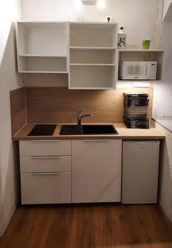 a kitchen with white cabinets and a sink at Hyper centre in Chambéry