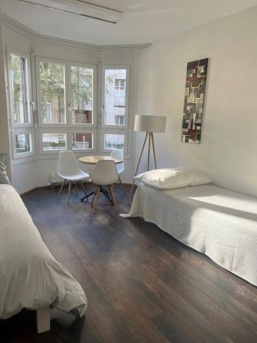 um quarto com uma cama, uma mesa e janelas em Basel-Stadt Gundeldingen Zimmer 403, WC in the hallway, outside the room em Basileia