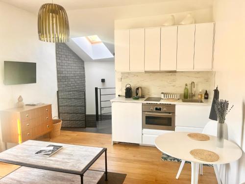 a kitchen and living room with white cabinets and a table at Les Cerises du Pont du Gard in Remoulins