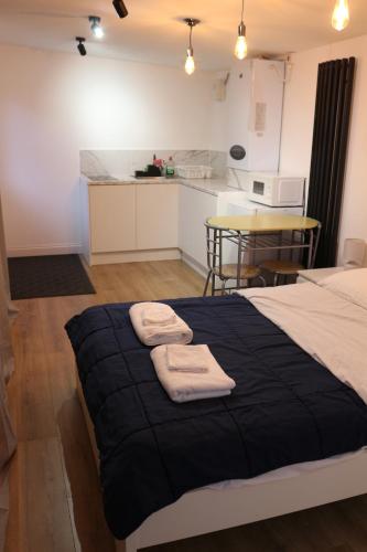 a bedroom with a large bed with towels on it at Self Contained, Garden Studio walking distance to Harry Potter Studio in Leavesden Green