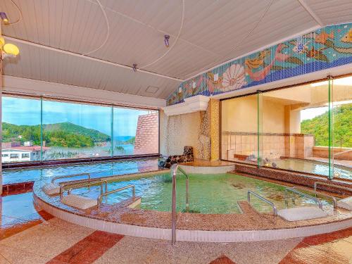 een groot zwembad in een gebouw met een groot raam bij Yukai Resort Unzen Toyokan in Obama