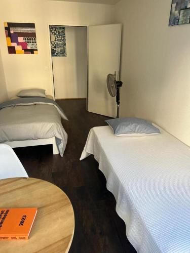 um quarto de hotel com duas camas e uma mesa em Basel-Stadt Gundeldingen Zimmer 402, WC in the hallway, outside the room em Basileia