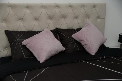 a black couch with two purple pillows on it at Lilien apartment Airport in Ledine