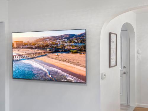 a flat screen tv hanging on a wall in a living room at Quaint Mid-Century Cottage by the Coast in Ventura
