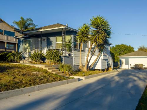 a house with a palm tree in front of a street at Quaint Mid-Century Cottage by the Coast in Ventura