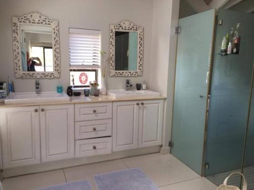 y baño con 2 lavabos, ducha y espejo. en Lakeside home in security estate with solar power en Ciudad del Cabo