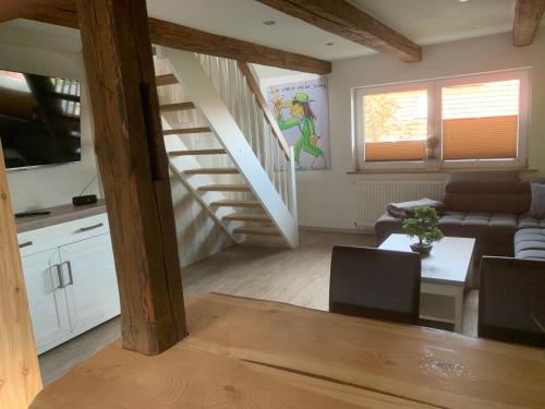 ein Wohnzimmer mit einer Treppe, einem Sofa und einem Tisch in der Unterkunft Ferienwohnung Am Graben in Hasselfelde