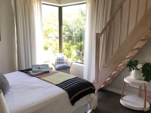 a bedroom with a bed and a large window at Lakeside home in security estate with solar power in Cape Town