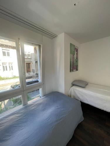 twee bedden in een kleine kamer met een raam bij Basel-Stadt Gundeldingen Zimmer 404, in Bazel
