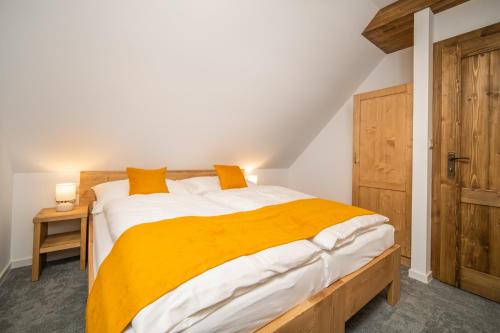 a bedroom with a large bed with a yellow blanket at Rezort pri jazere Podbanské in Pribylina