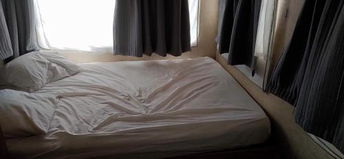 an unmade bed in a room with a window at Camping Chon du Tarn in Bédouès
