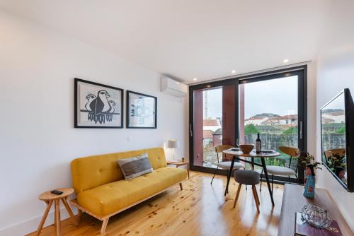 a living room with a yellow couch and a table at Fontainhas Royal in Porto
