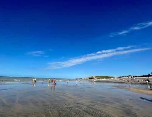a group of people standing in the water on a beach at Gite Les rives du Dun in Le Bourg-Dun
