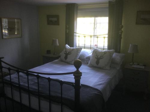 a bedroom with a bed with white sheets and a window at The Cottage in Wadhurst