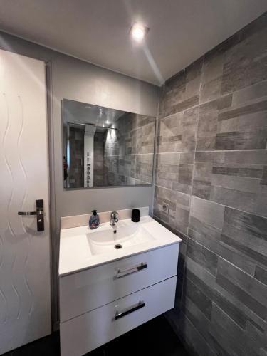 ein Bad mit einem Waschbecken und einem Spiegel in der Unterkunft Charmante maison Climatisé avec Netflix et Disney plus in Touet-de-lʼEscarène