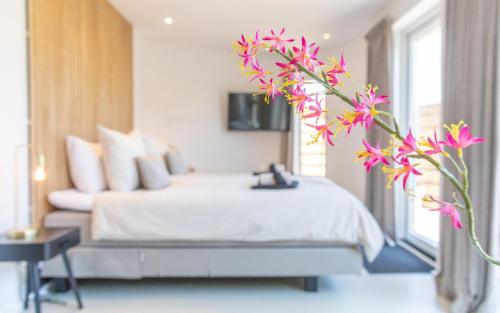 Bed & Bike Op Texel في دن بورخ: غرفة نوم مع سرير مع زهور وردية