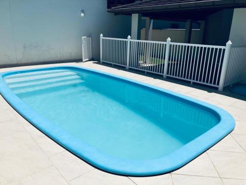 una gran piscina azul en un edificio en Townhouse composta por 4 triplex duas suítes a duas quadras do mar, en Barra de Ibiraquera