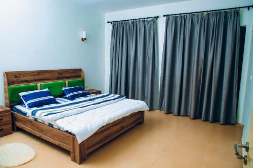 sypialnia z łóżkiem z niebieskimi i zielonymi poduszkami w obiekcie Saint Emmanuel near Kigali Convetion center w mieście Bugesera