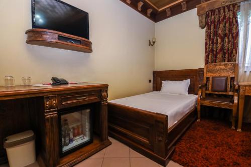 a bedroom with a bed and a tv and a chair at Brilant Antik Center in Tirana