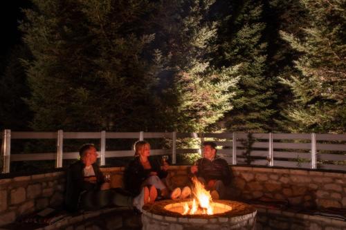 three people sitting around a fire pit at night at Casa de Madera in Pávliani