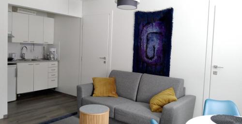 a living room with a gray couch and a kitchen at Kuukkeli Apartments Inari in Inari